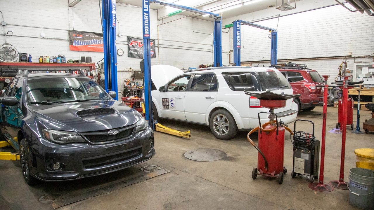Vehicles sit on and between two-post lifts in an auto repair shop service bay