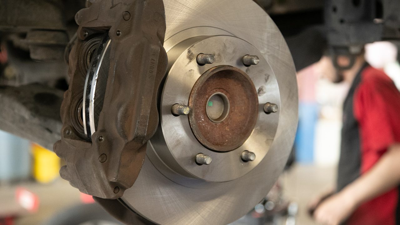 A newly installed brake rotor and brake caliper assembly on a vehicle in an auto repair service bay