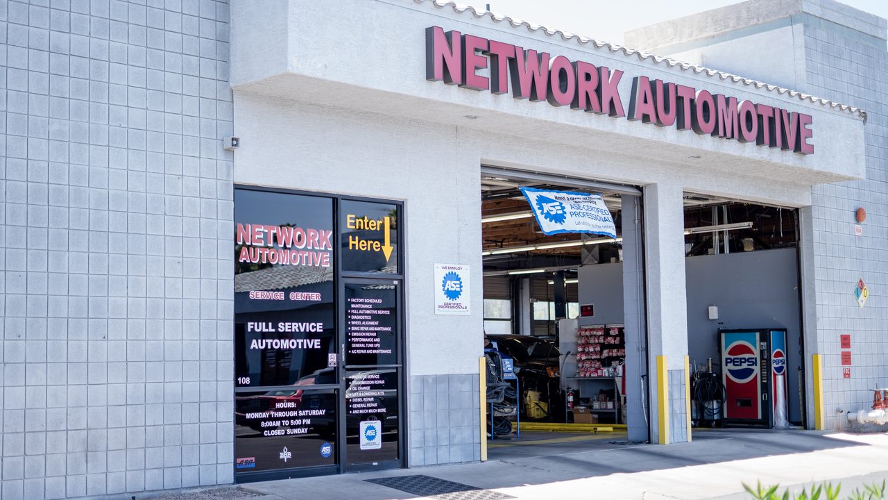 The exterior of an automotive service repair shop shows open service bays with equipment inside
