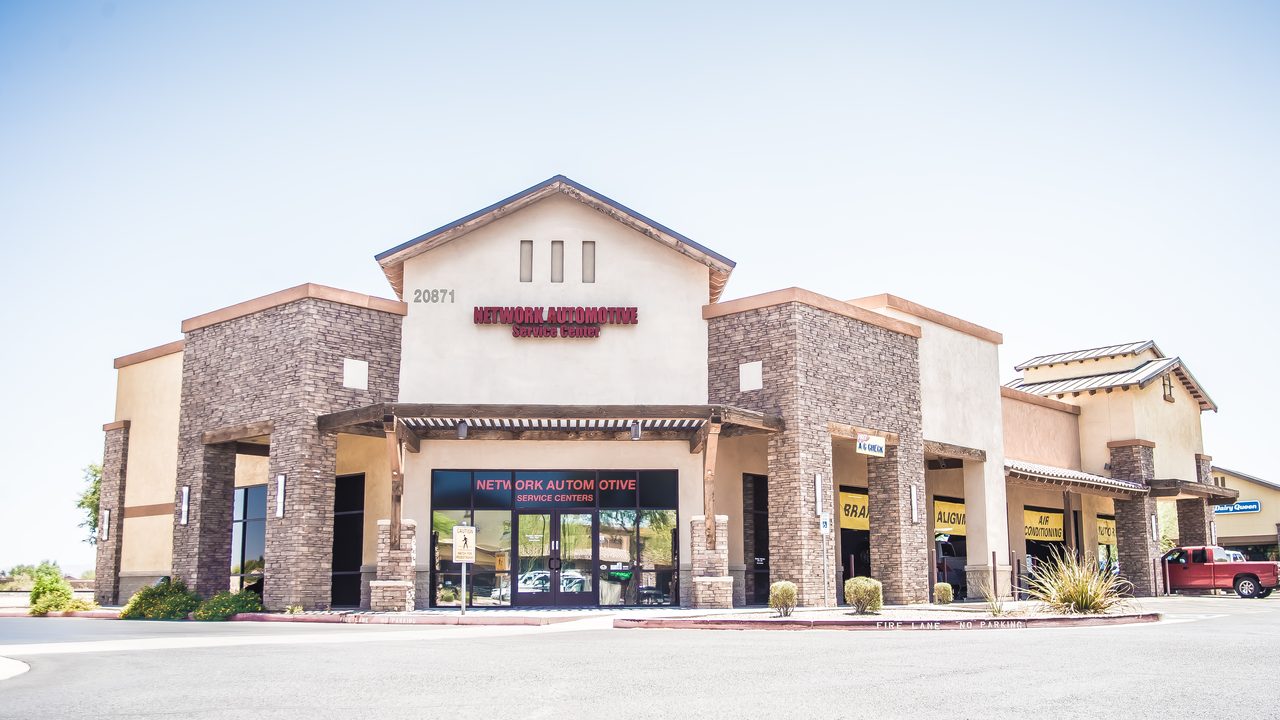 The exterior of an automotive service center features stone facade architecture and multiple service bays