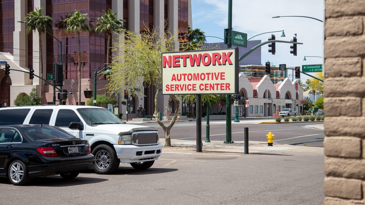 An outdoor view displays parked vehicles in front of a street sign for an automotive service center