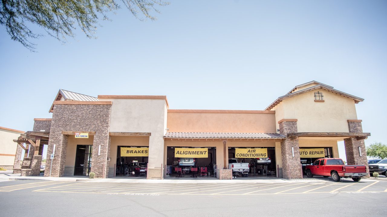 The exterior of an auto repair shop features multiple open service bays with vehicles undergoing maintenance