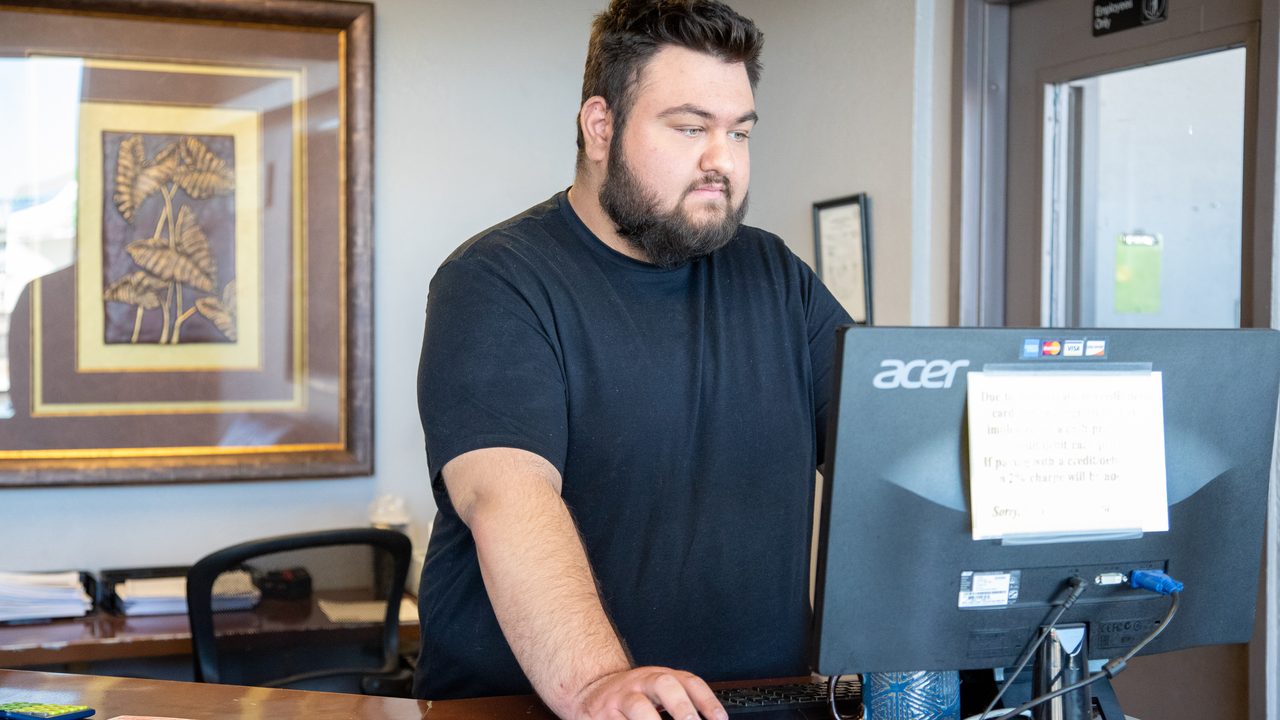 A shop service employee works on a computer at the front counter in the lobby