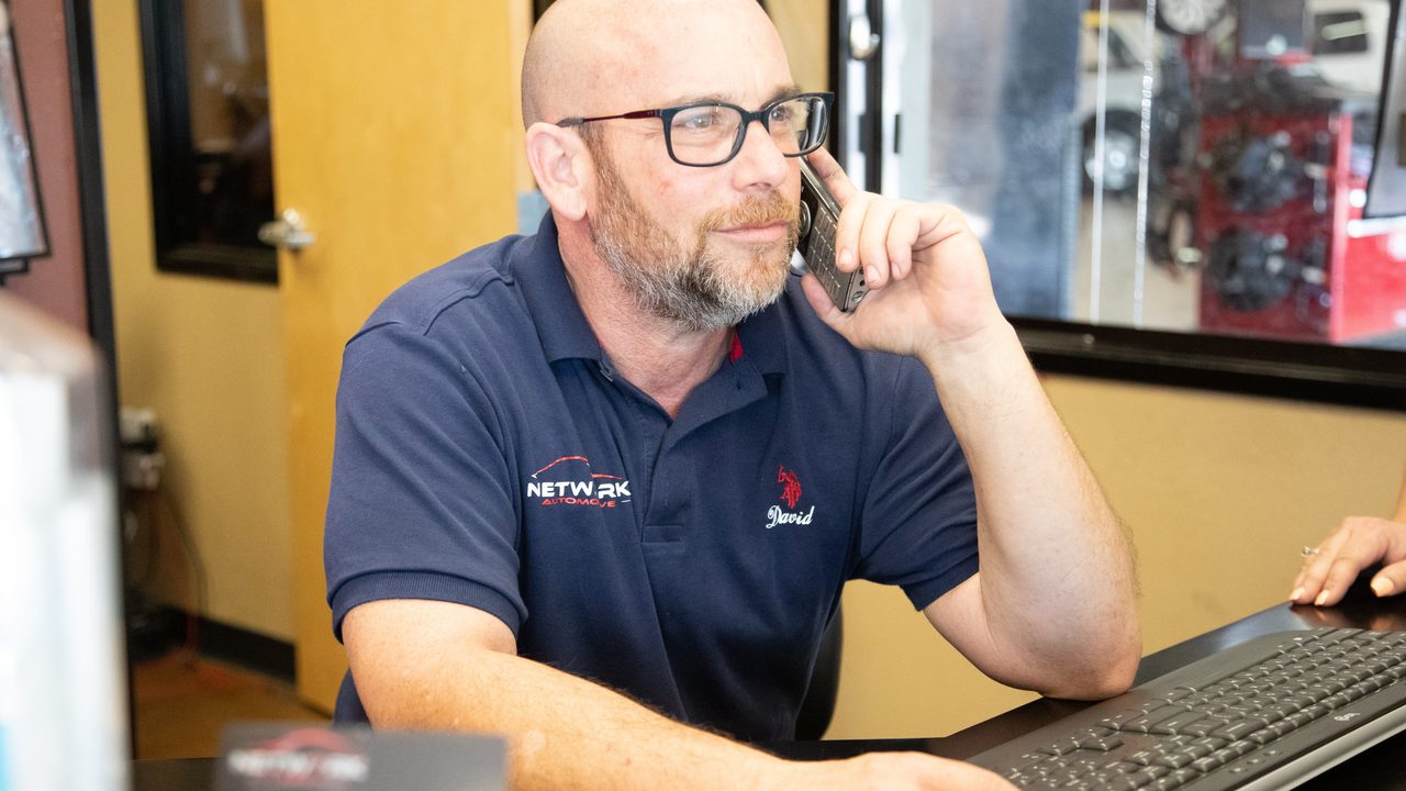 A service advisor talks on the phone while working at the front counter of an auto repair shop