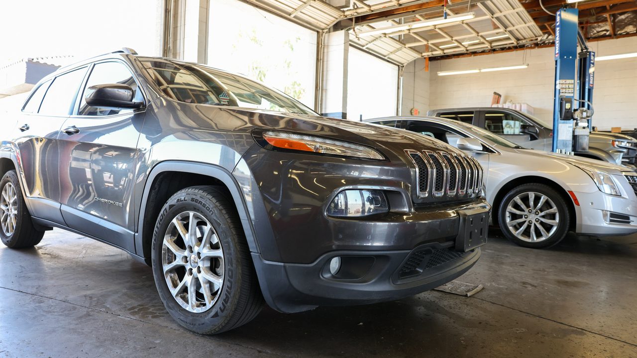 A dark gray SUV sits parked inside a bright auto repair shop service bay