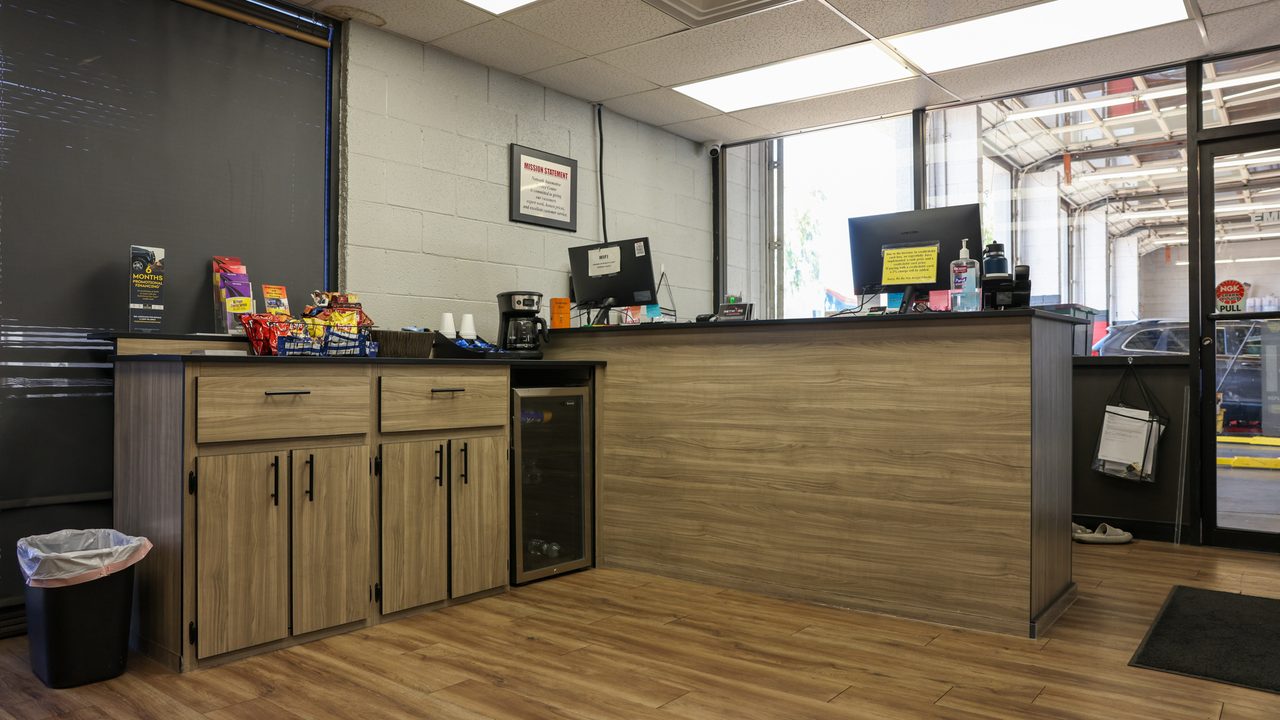 The empty front counter and customer lobby of an auto repair shop with windows overlooking the service bay