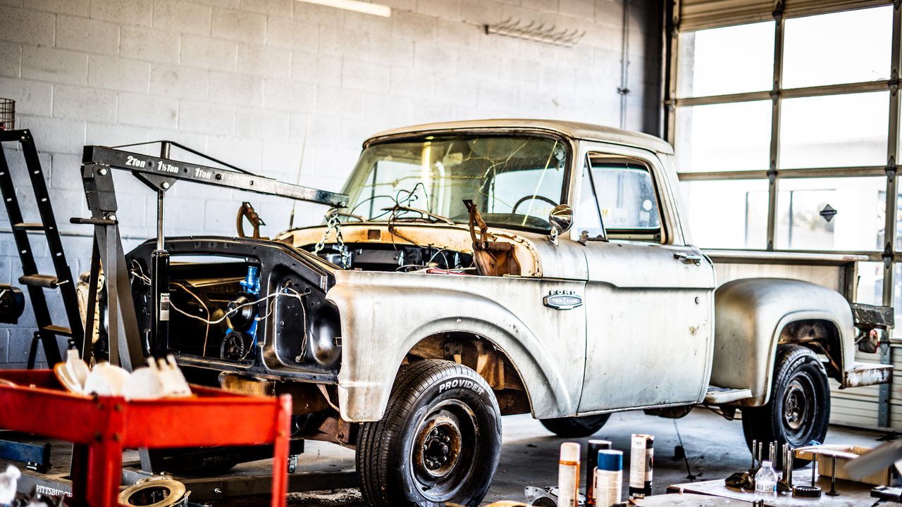A vintage pickup truck undergoes engine restoration inside an auto repair service bay