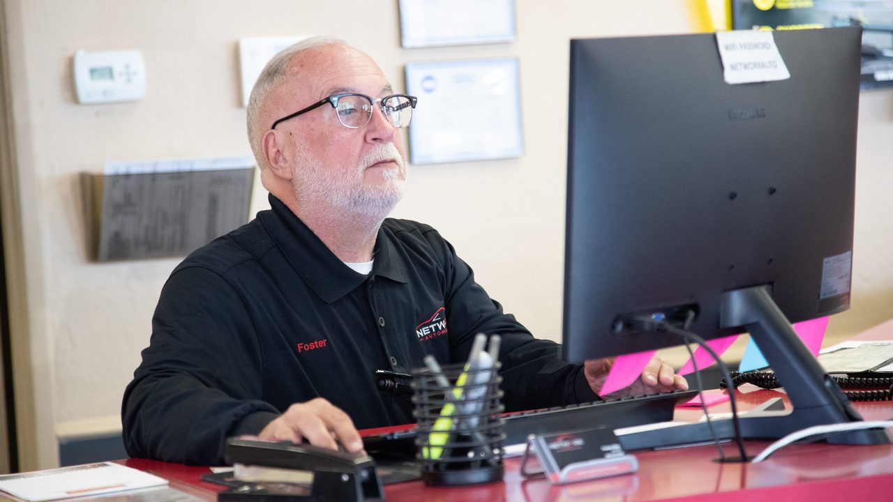A technician works at a computer monitor behind the front counter in an auto repair shop lobby