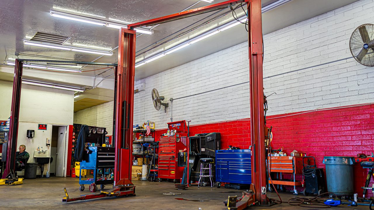 An auto repair service bay stands ready with two-post lifts and toolboxes lined along the walls