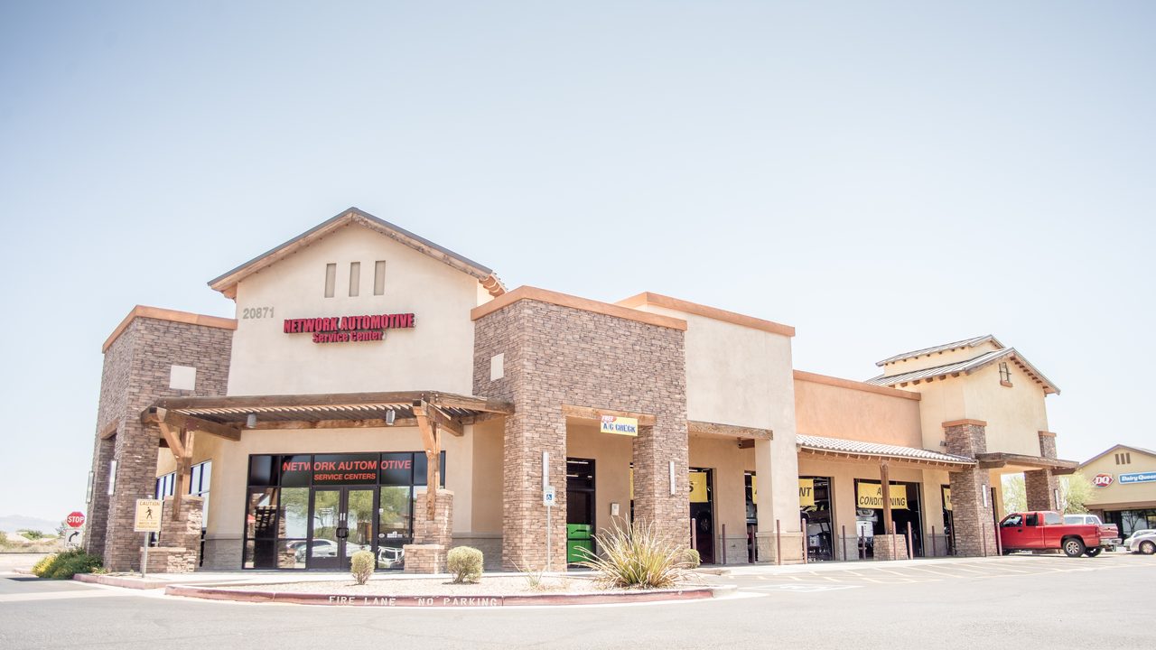 The exterior of an automotive service center showing its storefront, open service bays, and parked pickup truck